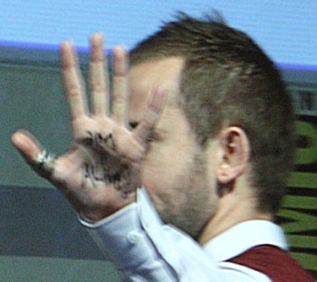 Dominic Monaghan at Comic-Con holding up hand which appears to say "Am I Alive?"